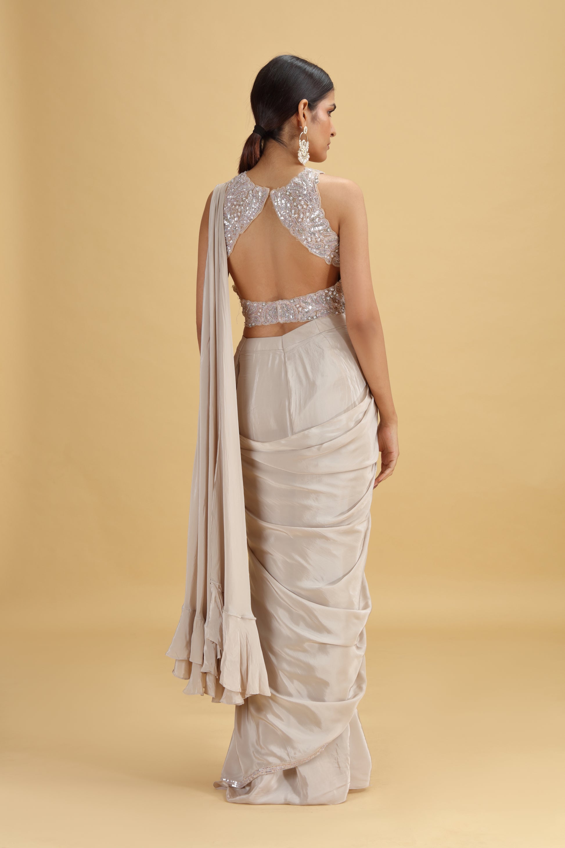 Woman wearing a saree with a beaded blouse on a beige background