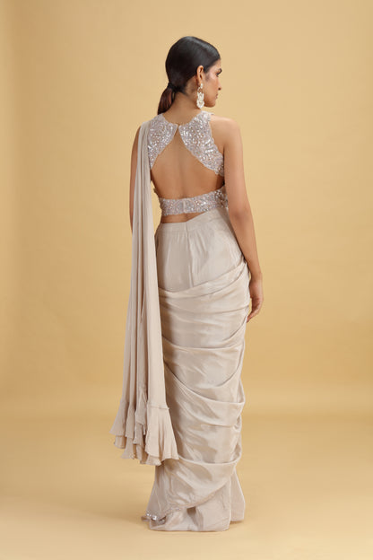 Woman wearing a saree with a beaded blouse on a beige background