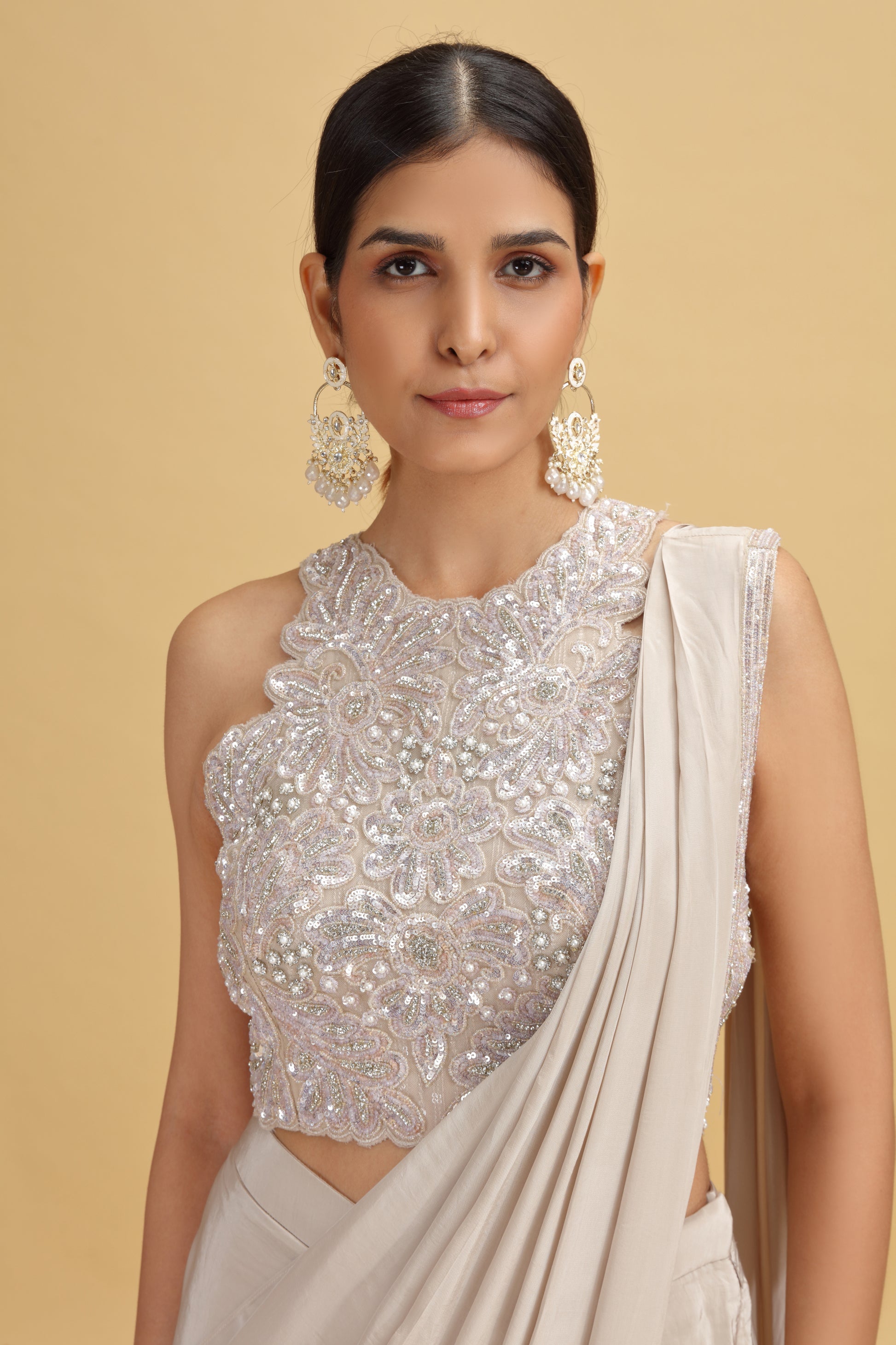 Woman wearing a heavy moti-sequins work blouse and beige saree
