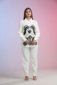 Woman wearing a white printed Co-ord Set with black floral design against a gradient background