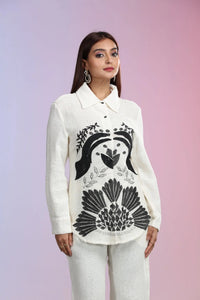 A woman wearing an ivory co-ord set consisting of white pants and a matching jacket.