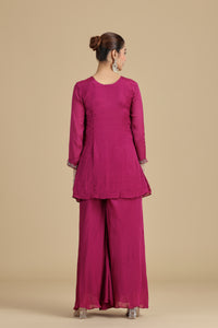 Woman wearing a magenta traditional outfit on a beige background