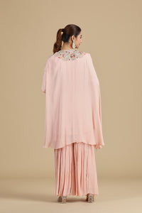 Woman wearing a light pink traditional outfit with floral embroidery on a beige background