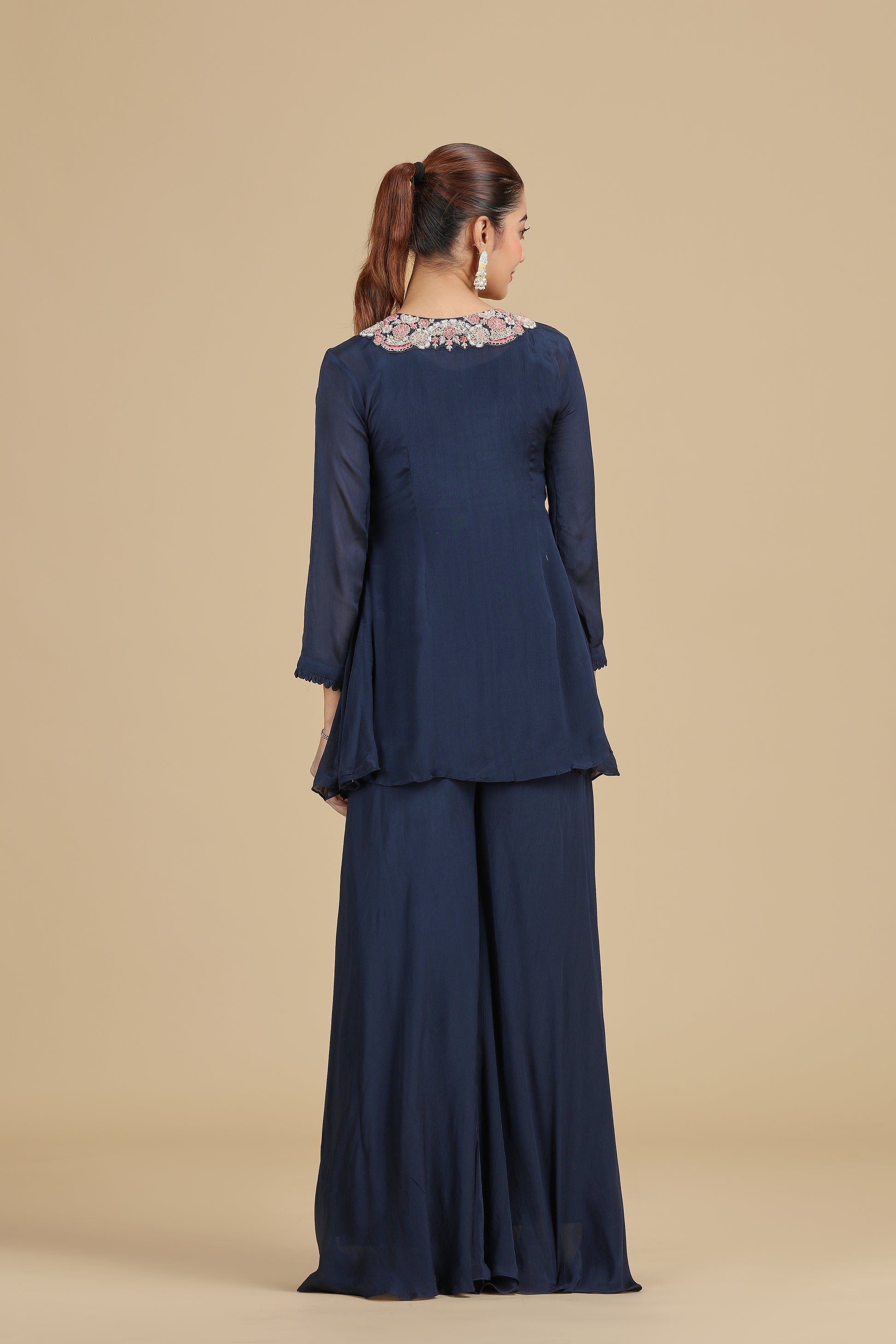 Woman wearing a navy blue outfit with floral embellishments on a beige background