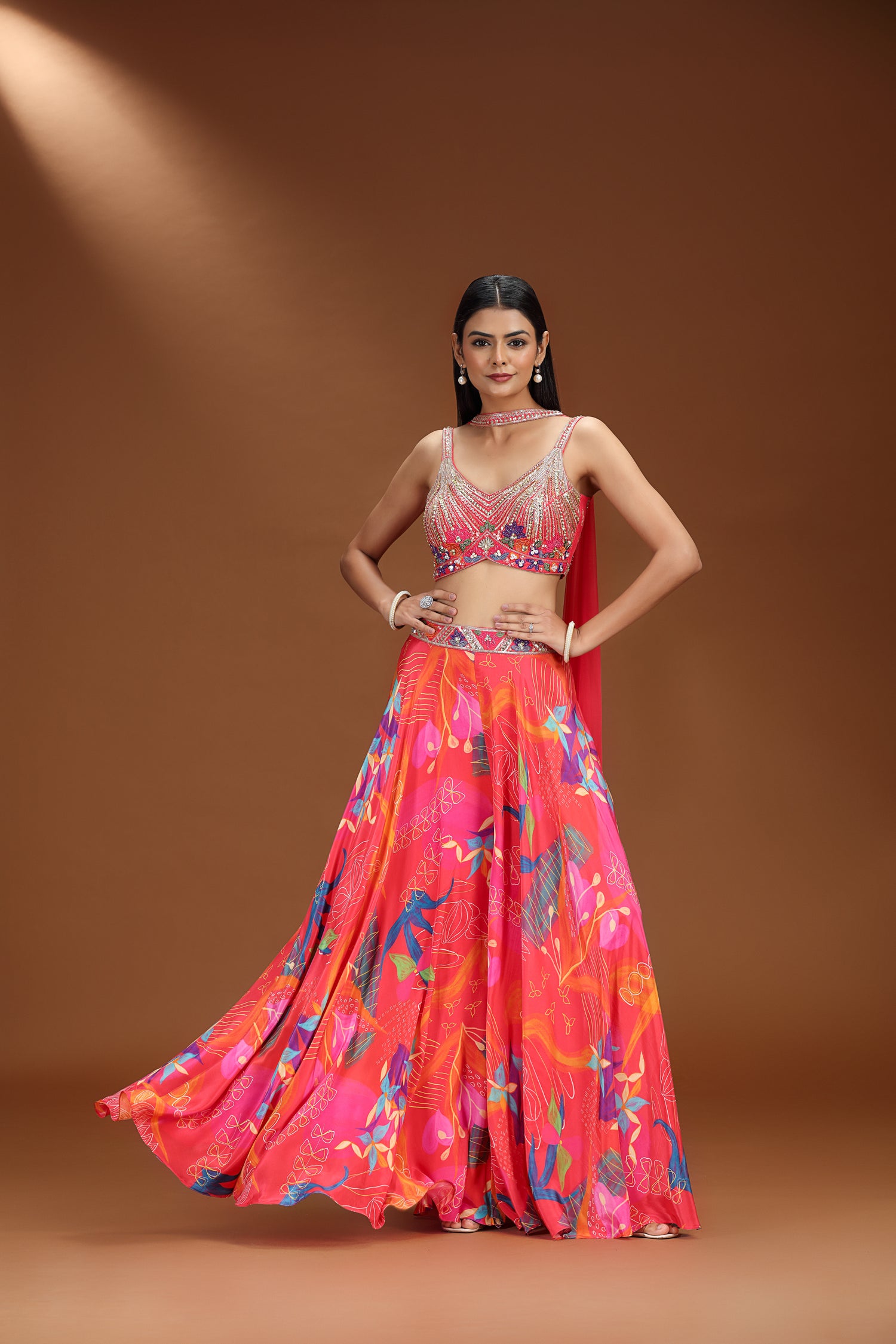Woman wearing a vibrant floral lehenga on a brown background