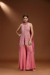 Woman wearing a pink salwar suit outfit with a matching dupatta against a brown background