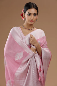 Close-up of a woman draped in a soft blush-pink Dola silk saree featuring delicate zari weaving and a subtle textured border