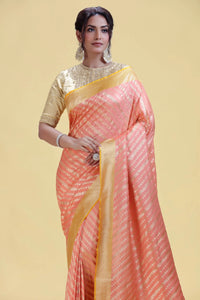 Woman wearing a peach saree with yellow border on a beige background