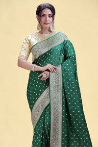 Woman in elegant green saree with gold patterns cream blouse against a soft yellow background