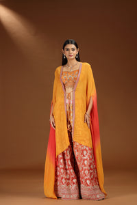 Woman wearing a orange salwar suit with a yellow dupatta against a brown background