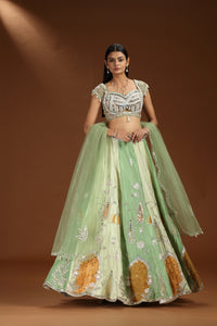 Woman wearing a traditional green and white embroidered lehenga 