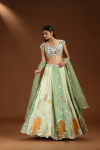 Woman wearing a traditional green and white embroidered lehenga on a brown background