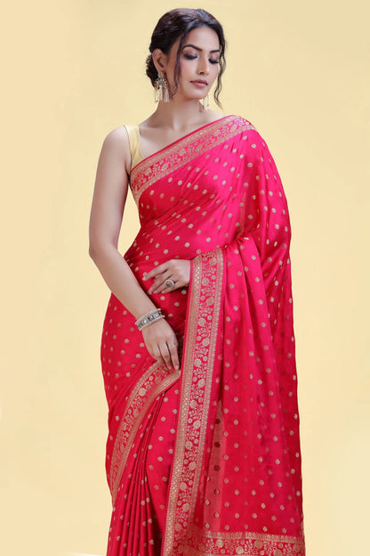 Woman in a vibrant red saree with gold detailing, wearing elegant silver jewelry, standing against a soft yellow background