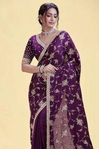 Woman wearing a purple saree with floral patterns on a beige background
