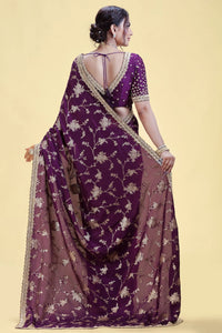 Woman wearing a purple saree with floral patterns on a beige background