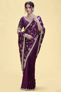 Woman wearing a purple saree with gold border on a beige background