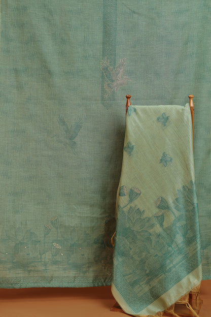 Green floral-patterned towel hanging on a wooden rack against a textured green wall.