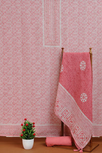 Pink patterned fabric on a wooden rack against a matching wall with a small plant on a brown surface.