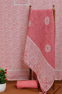Pink fabric with white patterns on a wooden stand against a patterned wall.