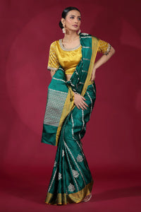 Woman wearing a green and gold saree against a red background