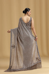 Woman wearing a silver saree with a beige background