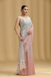 Woman wearing a light gray and pink saree with a beige background