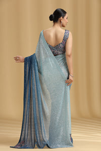 Woman wearing a sea green blue saree with a beige background