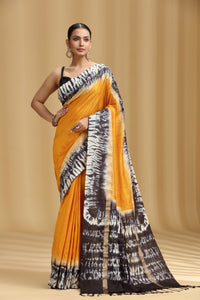Woman wearing a yellow and black patterned saree on a beige background