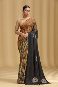 Woman wearing a saree with a zebra pattern and black border against a beige background