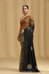 Woman wearing a traditional saree with a black and gold pattern on a beige background
