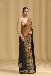 Woman wearing a black and orange saree with a beige background