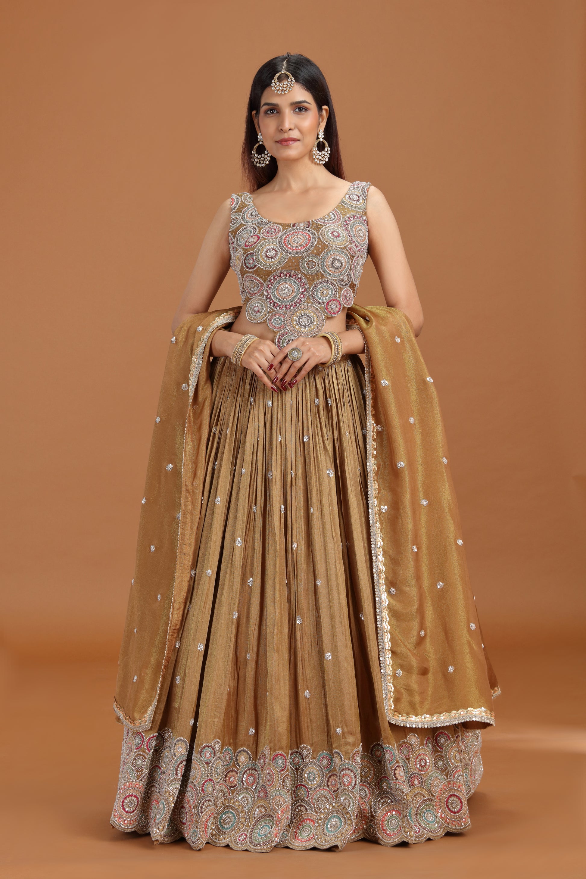 Woman wearing a traditional dusty gold sequin work lehenga set by Roopkala 
