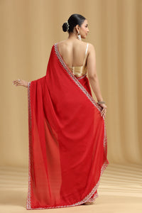 Woman wearing a red silk saree with a gold blouse against a beige background