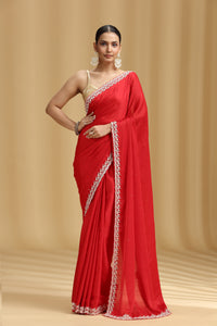 Woman wearing a red saree with white border on a beige background
