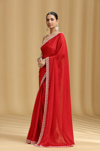 Woman wearing a red  crepe saree with a beige background