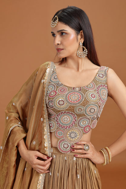 Woman wearing a dusty gold tissue lehenga with aari pearl work