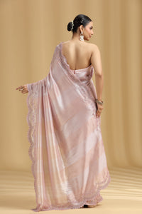 Woman wearing a light pink saree with a beige background