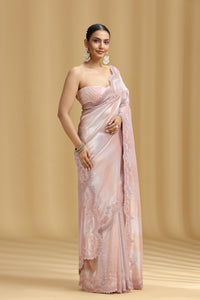 Woman wearing a pink organza tissue saree with a beige background