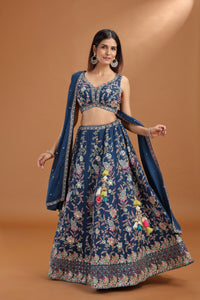 Woman wearing a blue floral lehenga with a matching dupatta on a brown background