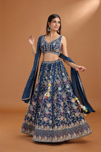 Woman wearing a blue floral lehenga with a matching dupatta on a brown background