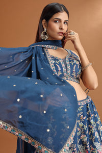 Woman wearing a blue embroidered traditional outfit on a brown background