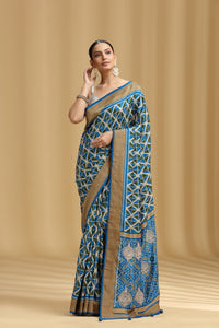 Woman wearing a blue and beige saree with intricate patterns on a beige background