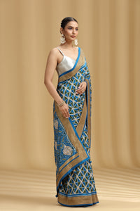 Woman wearing a blue and beige saree with a geometric pattern on a beige background