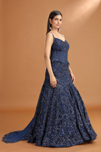 Woman wearing a navy blue evening gown against a brown background