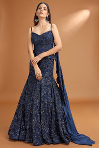 Woman wearing a blue evening gown with a cape against a brown background