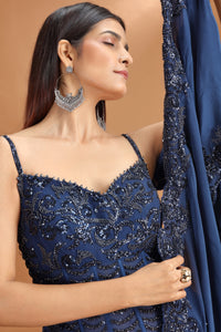 Woman wearing a blue embroidered dress with a plain background