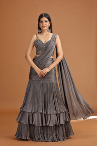 Woman wearing a grey crepe lehenga  with a brown background