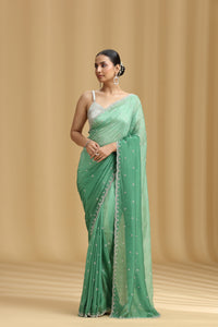 Woman wearing a green crepe saree with a beige background
