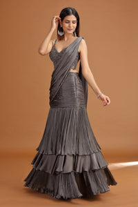 Woman wearing a dark grey lehenga crepe skirt against a brown background