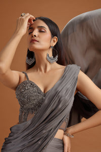 Woman in a grey blouse and dupatta with intricate detailing lehenga on a brown background